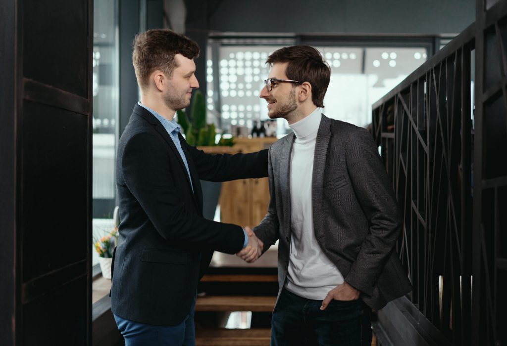 Two young businessmen greeting each other, shaking hand